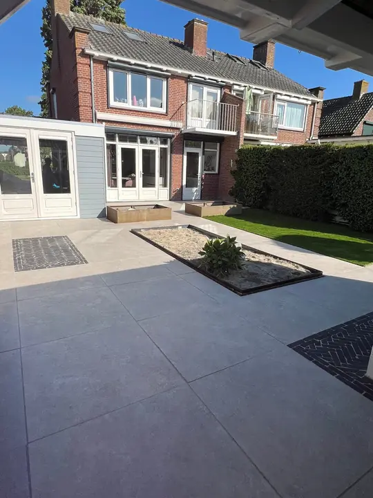 Lichtgrijs terras met plantvak achter een rijtjeswoning