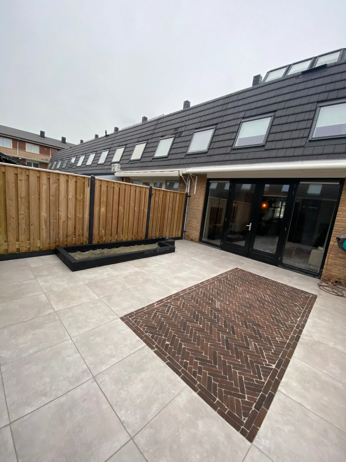 Vlak van rode klinkers in visgraat midden in een licht terras