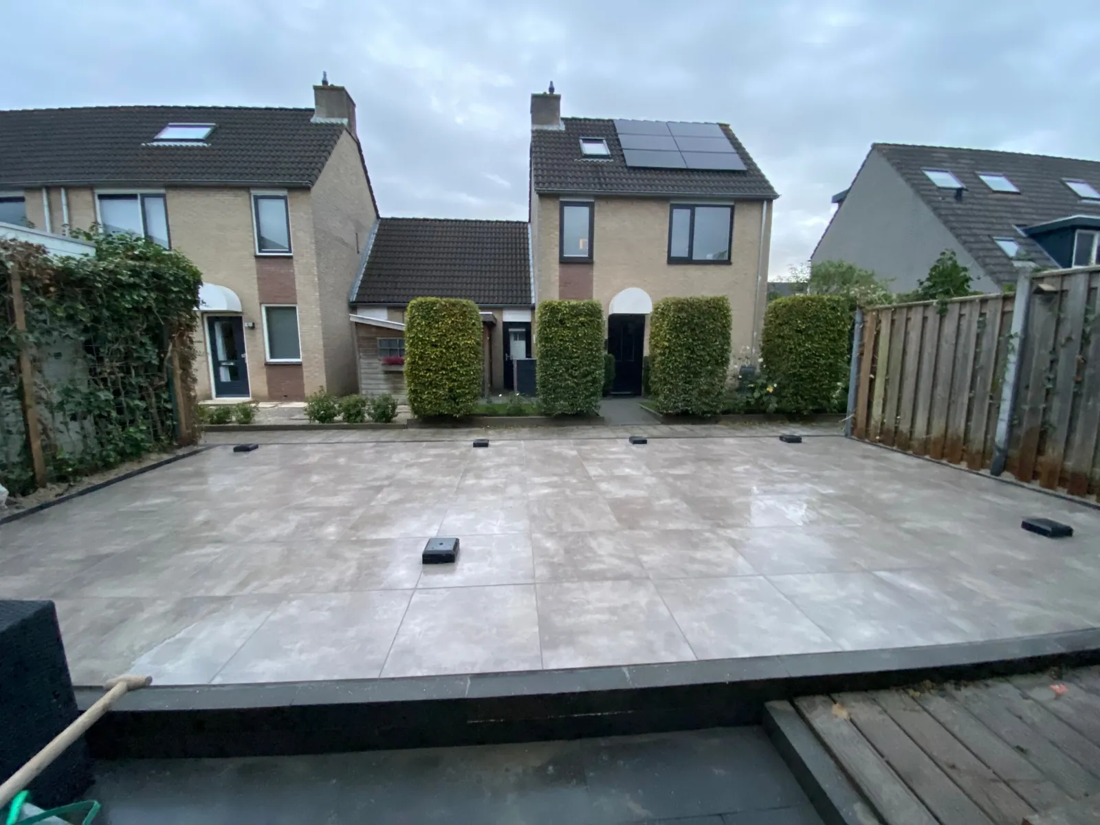 Verhoogd lichtgrijs terras met een houten vlonder op de voorgrond