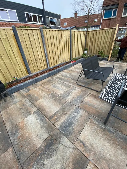 Terras met gevlamde tegels en een zithoek voor een nieuwe schutting
