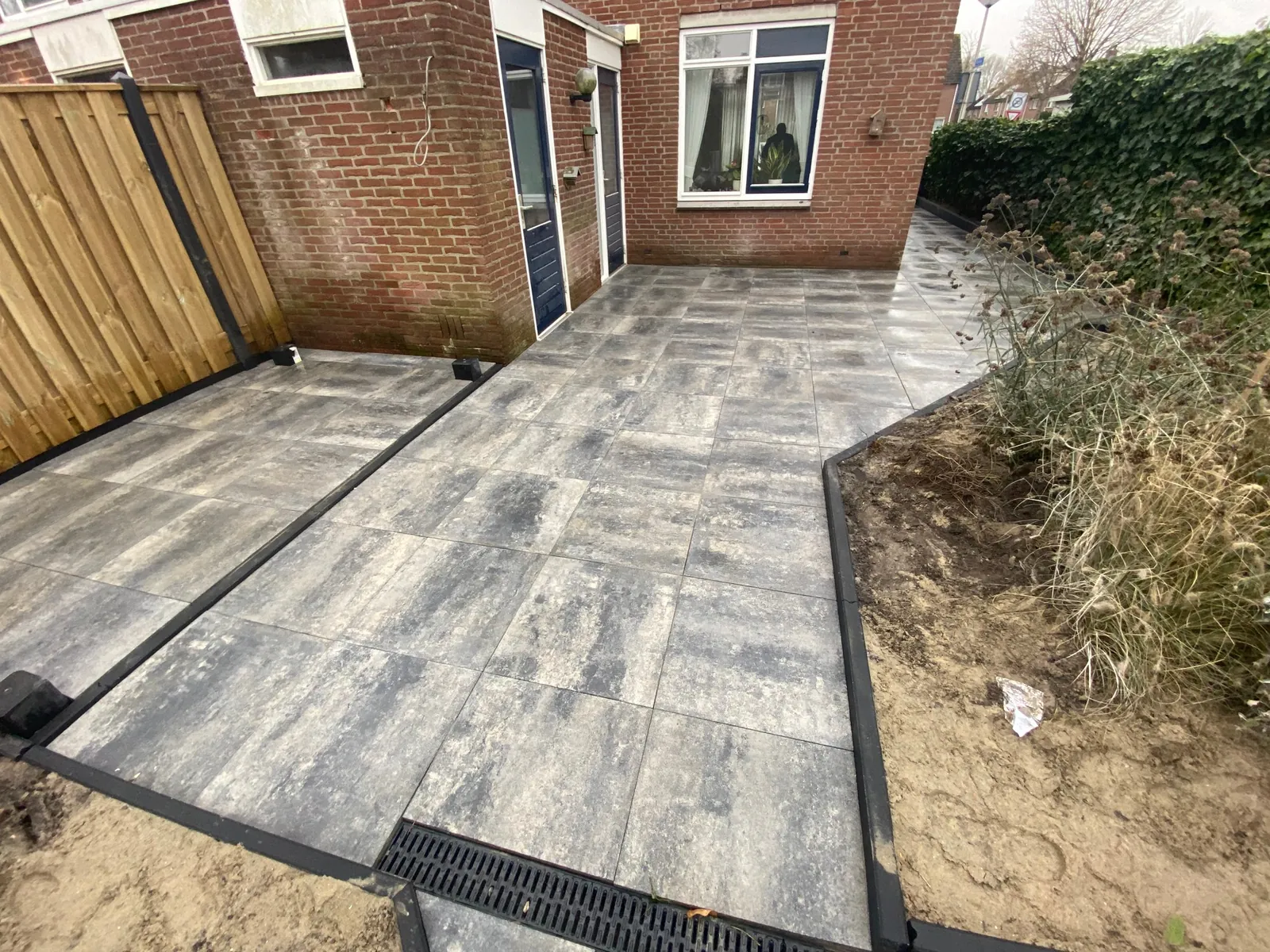 Strak aangesloten bestrating met een afvoergoot langs de gevel
